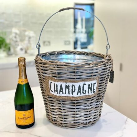 Kubu Rattan Champagne Cooler with burlap label next to a champagne bottle on a white marble benchtop