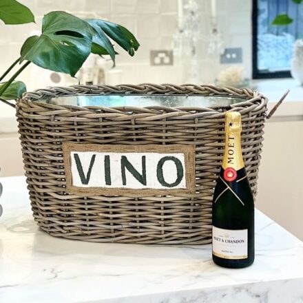 Kubu Vino Cooler Basket with a bottle of champagne next to it on a white marble surface