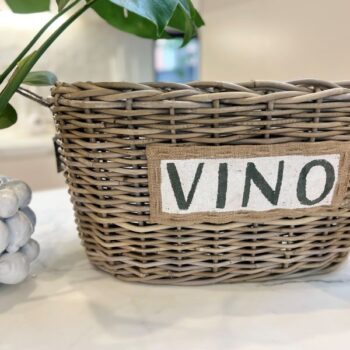 Kubu Vino Cooler Basket with a bottle of champagne next to it on a white marble surface
